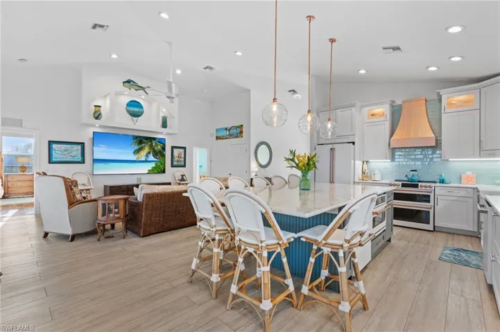 Kitchen featuring premium range hood, white cabinetry, high quality appliances, decorative light fixtures, and vaulted ceiling