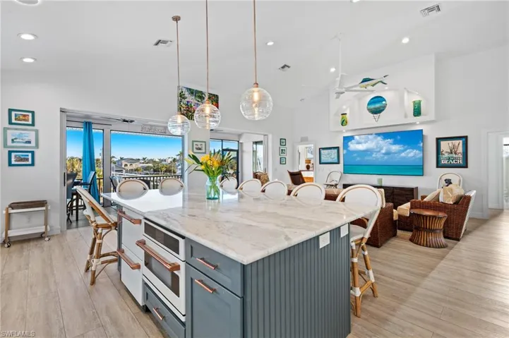Kitchen featuring ceiling fan, gray cabinetry, light stone countertops, decorative light fixtures, and light wood-type flooring