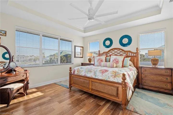 Bedroom with multiple windows, crown molding, a raised ceiling, and ceiling fan