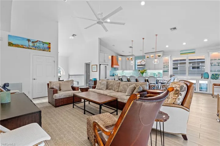 Living room with ceiling fan, high vaulted ceiling, and light wood-type flooring