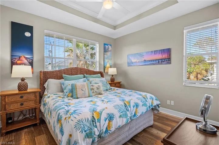 Bedroom with ceiling fan, a raised ceiling, and multiple windows