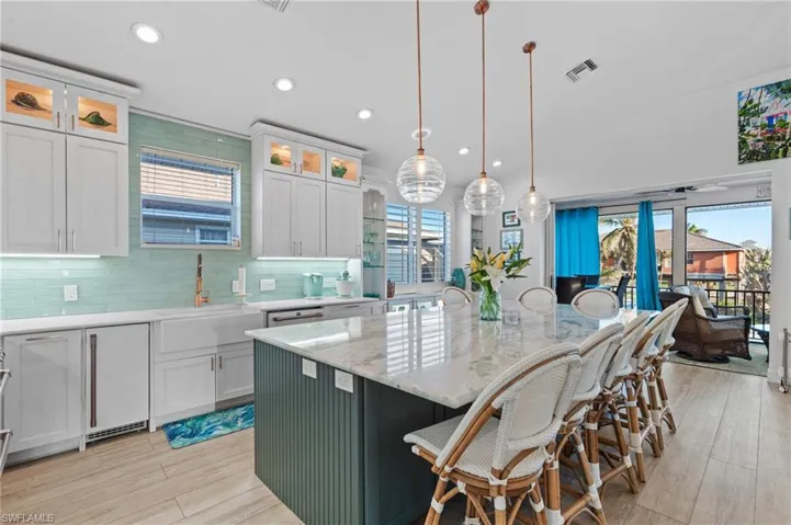 Kitchen with sink, a center island with sink, white cabinets, pendant lighting, and backsplash