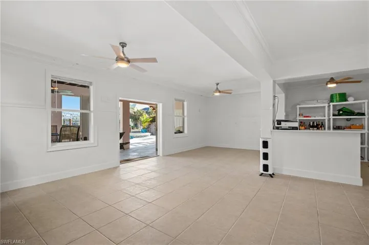 Unfurnished living room with crown molding, ceiling fan, and light tile patterned floors