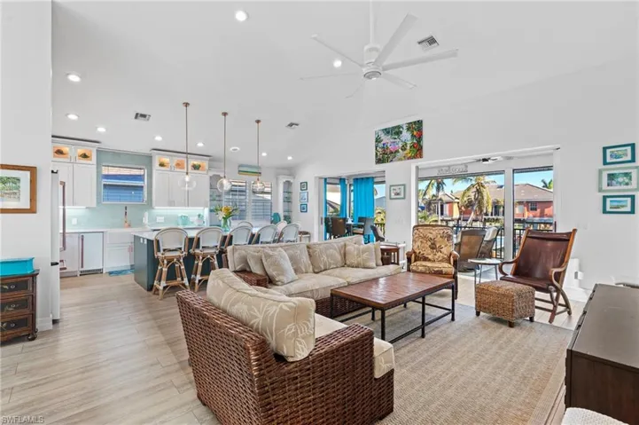 Living room with ceiling fan, high vaulted ceiling, and light wood-type flooring