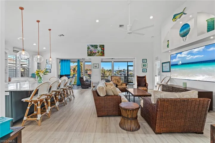 Living room featuring high vaulted ceiling, ceiling fan, and light wood-type flooring