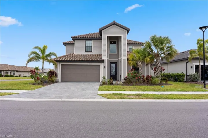 View of front of house featuring a tile roof, decorative driveway, a front yard, and a garage