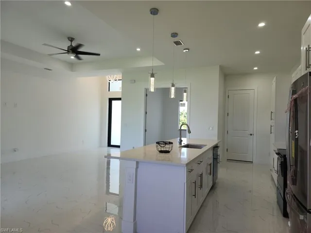 Kitchen featuring white cabinets, a center island with sink, sink, light tile patterned floors, and ceiling fan
