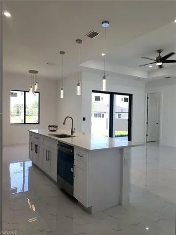 Kitchen with sink, light tile patterned flooring, dishwasher, and white cabinets