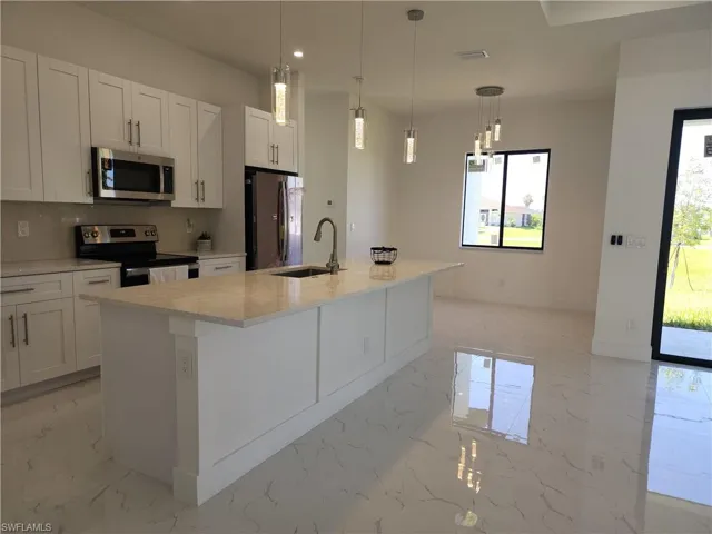 Kitchen featuring light tile patterned floors, a kitchen island with sink, appliances with stainless steel finishes, decorative backsplash, and sink