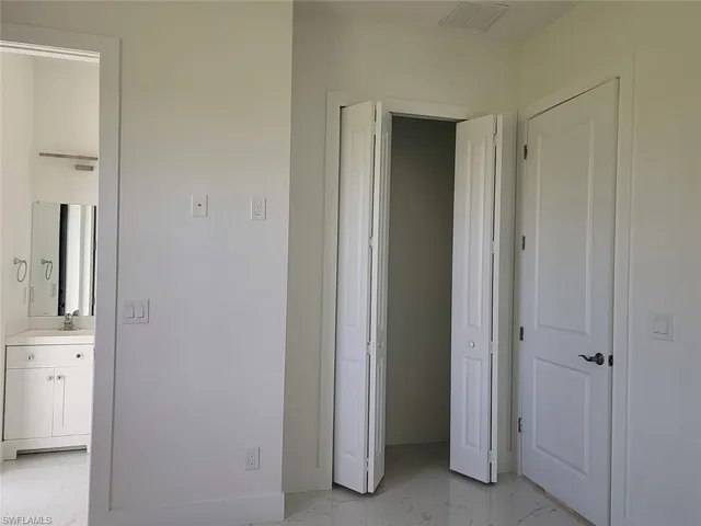 Unfurnished bedroom featuring sink, light tile patterned flooring, and ensuite bath