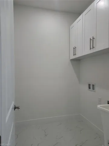 Laundry room with sink, washer hookup, cabinets, and light tile patterned floors