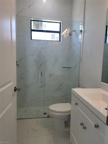 Bathroom with tile patterned flooring, a shower with door, toilet, and vanity