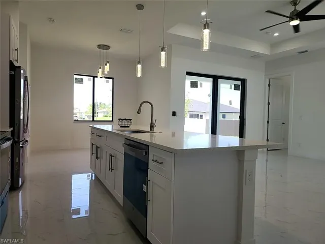 Kitchen featuring white cabinetry, a raised ceiling, a kitchen island with sink, and light tile patterned floors