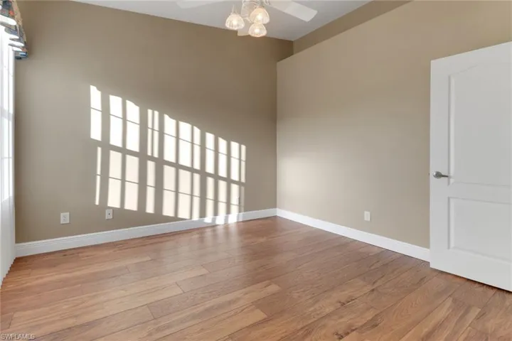 Guest bedroom featuring baseboards, ceiling fan, wood finished floors and lots of natural light