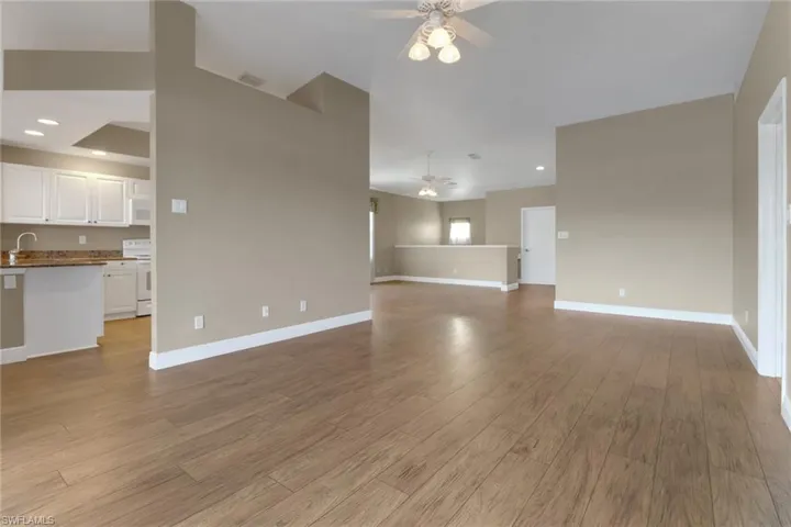 Unfurnished living room with light wood-style flooring, baseboards, and ceiling fan