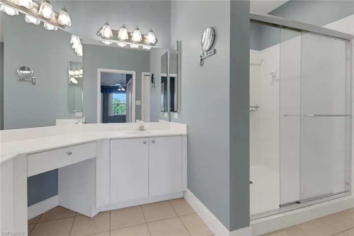Main Bathroom featuring a stall shower, baseboards, tile patterned flooring, and vanity