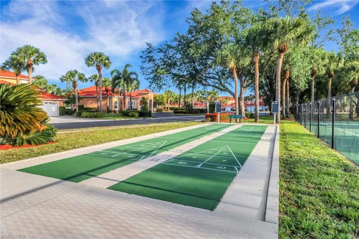 View of community with a lawn, fence, and shuffleboard
