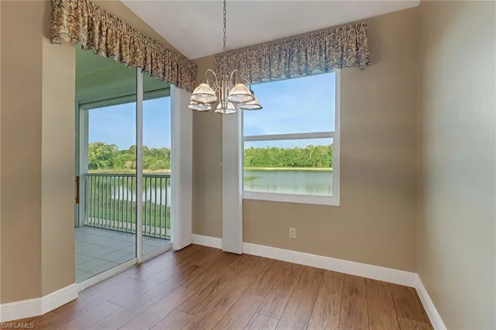 Eat in kitchen with chandelier, a water view, baseboards, and wood finished floors