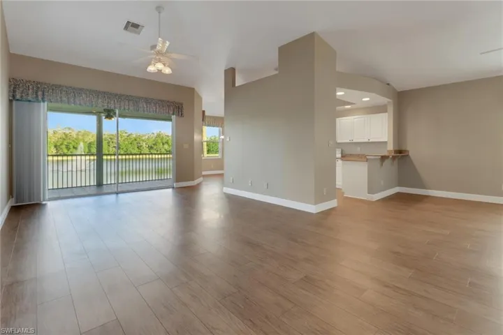 Unfurnished living room with baseboards, ceiling fan, and light wood-style floors overlooking screened lanai