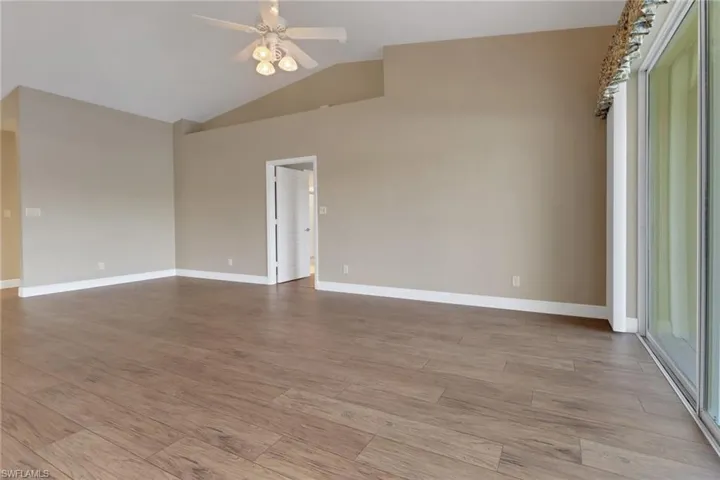 Family room with baseboards, vaulted ceiling, wood finished floors, and a ceiling fan