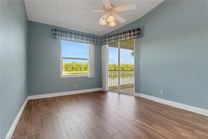 Main bedroom with a ceiling fan, baseboards, vaulted ceiling, wood finished floors overlooking the lake
