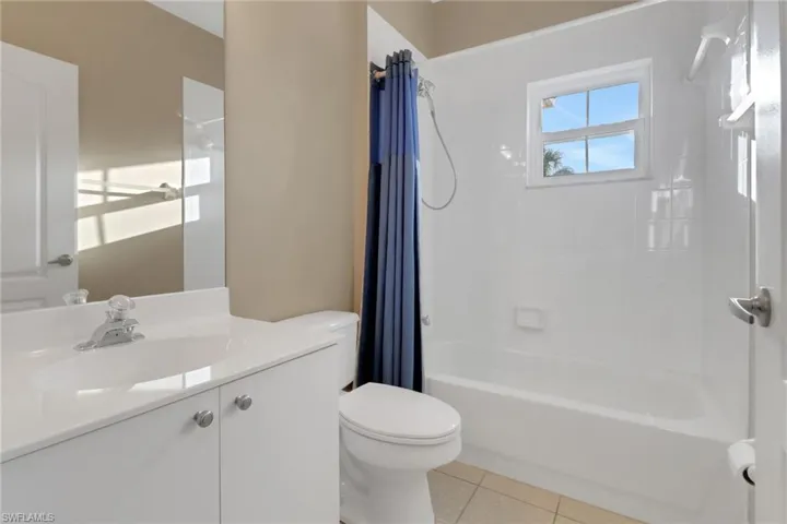 Full bathroom with shower / tub combo, toilet, tile patterned flooring, and vanity