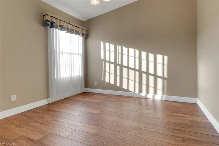 Guest bedroom with baseboards and wood finished floors