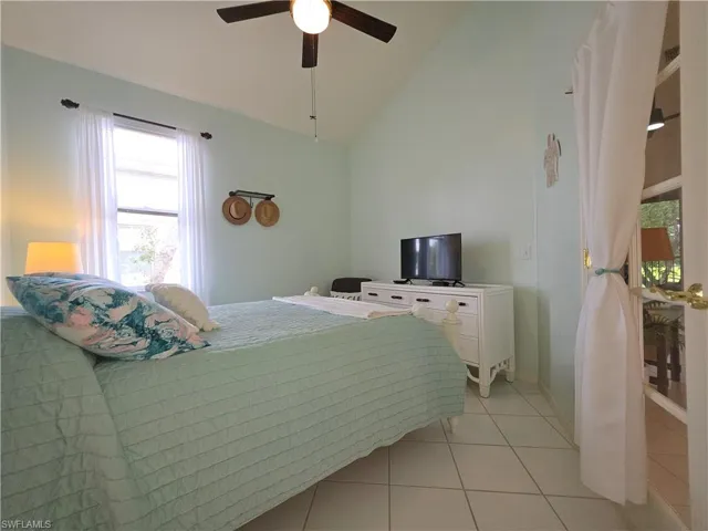 Bedroom featuring lofted ceiling, a ceiling fan, and light tile patterned floors
