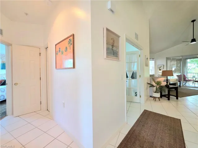 Hallway with light tile patterned flooring and vaulted ceiling