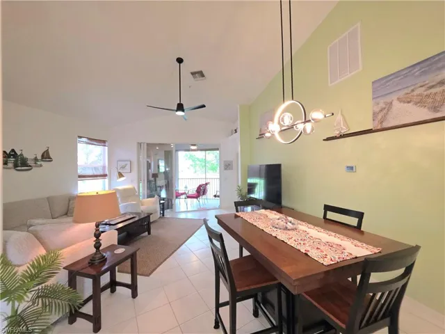 Dining space with vaulted ceiling, light tile patterned floors, and a ceiling fan