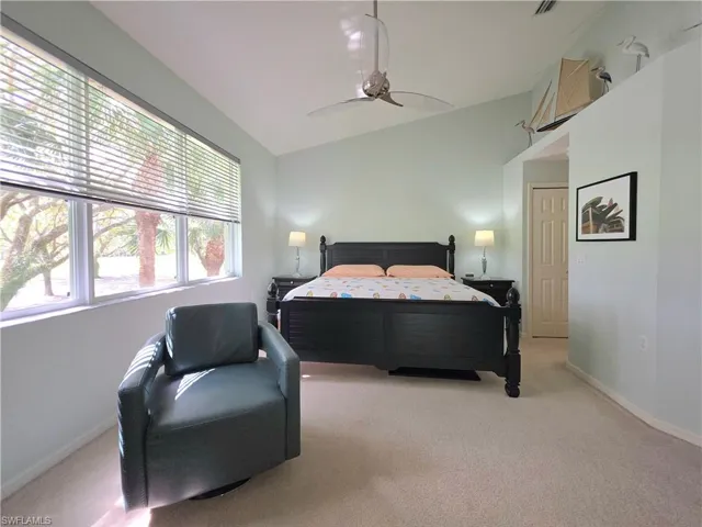 Bedroom featuring vaulted ceiling, light colored carpet, and ceiling fan