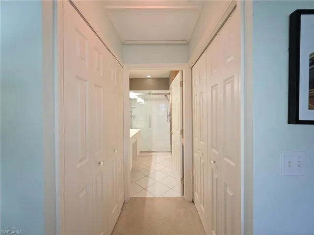 Hall with light tile patterned floors and light carpet