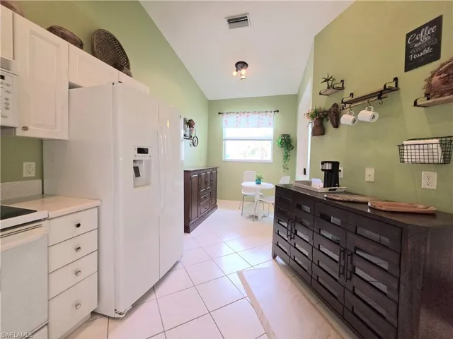 Full bathroom with light tile patterned floors, vaulted ceiling, and vanity