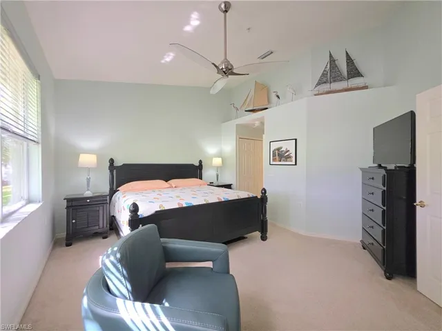 Bedroom with light colored carpet, ceiling fan, and a high ceiling