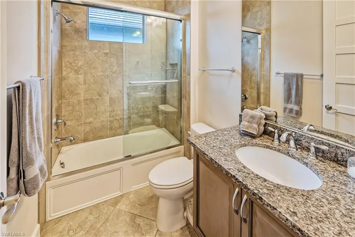 Full bathroom with shower / bath combination with glass door, vanity, and toilet