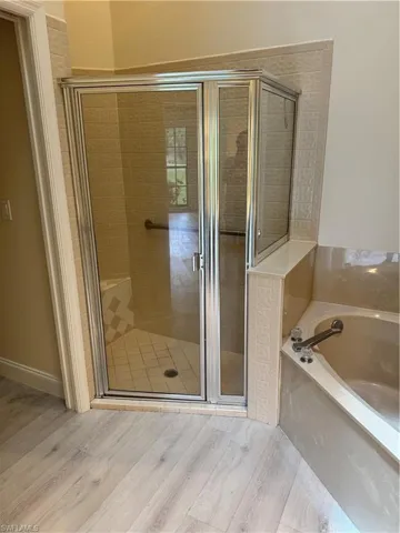 Glass-enclosed shower with a tiled interior, built-in bench, and grab bar, featuring a coordinating built-in tub with a deck-mounted faucet