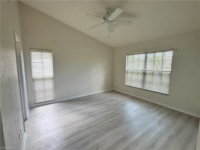 Spacious room featuring wood-finish flooring, vaulted ceilings, and a ceiling fan