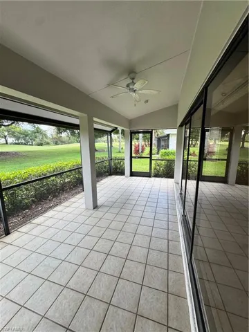 Screened patio featuring square tile flooring, a vaulted ceiling, a ceiling fan, and sliding glass doors