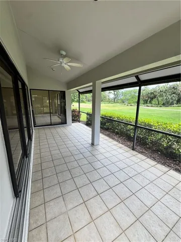 Expansive screened patio featuring square light-toned tile flooring, a white ceiling fan, and large sliding glass doors providing access to the interior