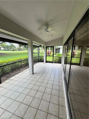 Screened outdoor patio featuring light-toned tile flooring and a vaulted ceiling with a ceiling fan