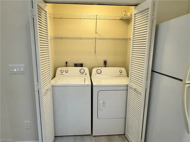 Dedicated laundry area featuring a washer and dryer, louvered bi-fold doors, and integrated wire shelving