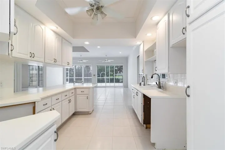 Kitchen featuring kitchen peninsula, sink, white cabinetry, and ceiling fan