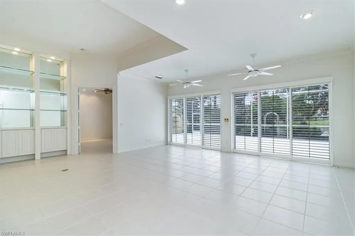 Tiled spare room with ceiling fan and crown molding