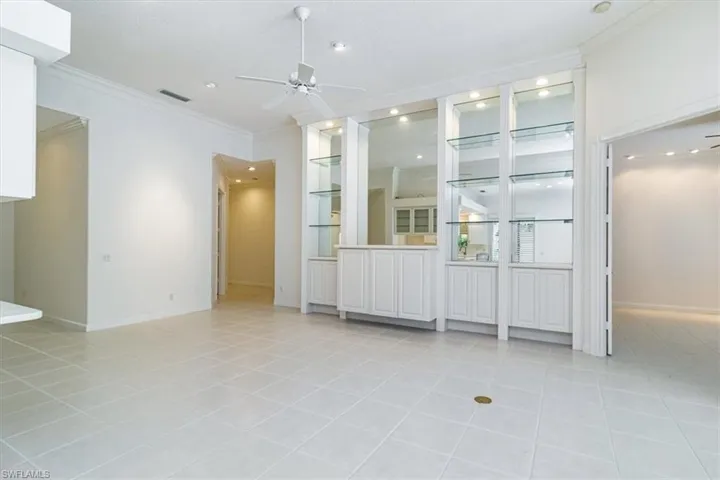Tiled spare room featuring ornamental molding, built in features, and ceiling fan