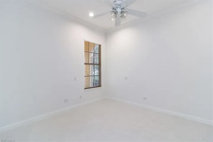 Empty room with light tile patterned flooring, crown molding, and ceiling fan