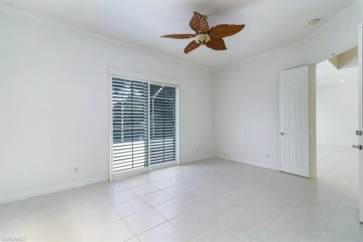Tiled empty room featuring ornamental molding and ceiling fan
