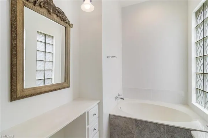 Bathroom featuring vanity and tiled bath