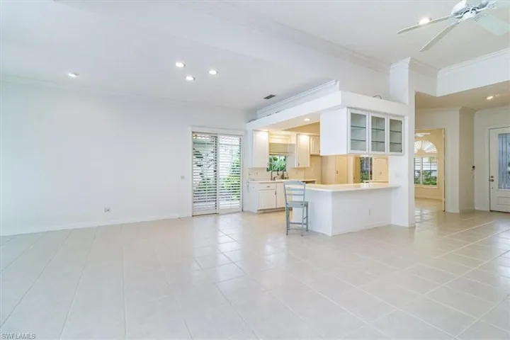 Unfurnished living room with plenty of natural light, light tile patterned flooring, ornamental molding, and ceiling fan