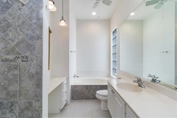 Bathroom with vanity, ceiling fan, a bathing tub, and tile patterned floors