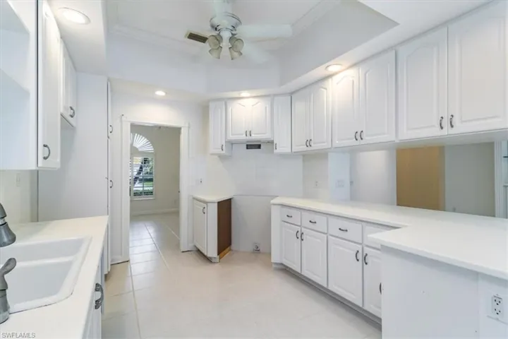 Laundry area featuring sink, light tile patterned flooring, ceiling fan, and crown molding